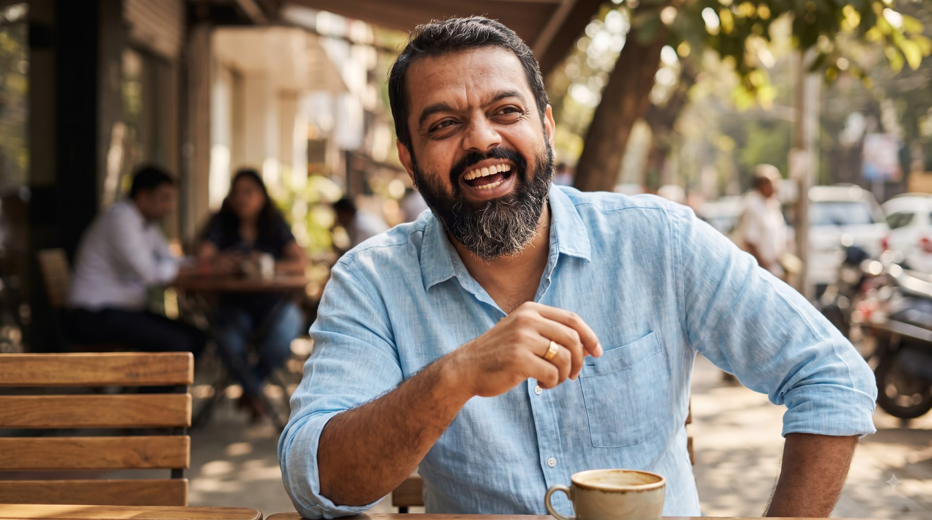 Chaitanya Bailey laughing during a conversation at an outdoor cafe